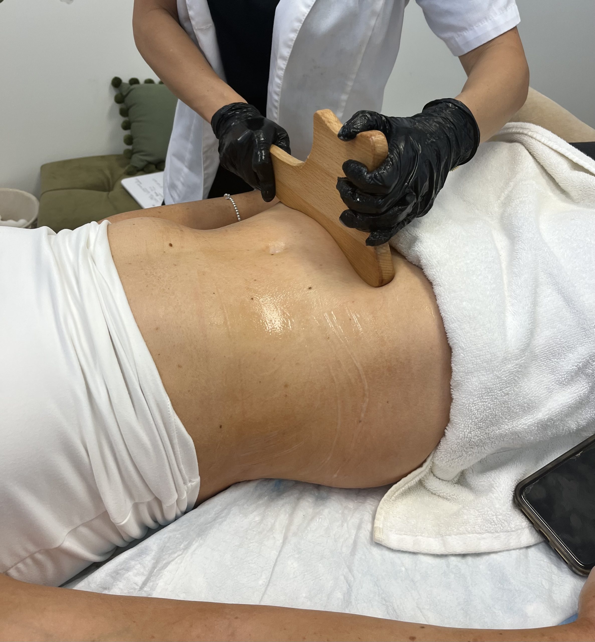 Woman on massage table receiving body sculpting services for fat loss.